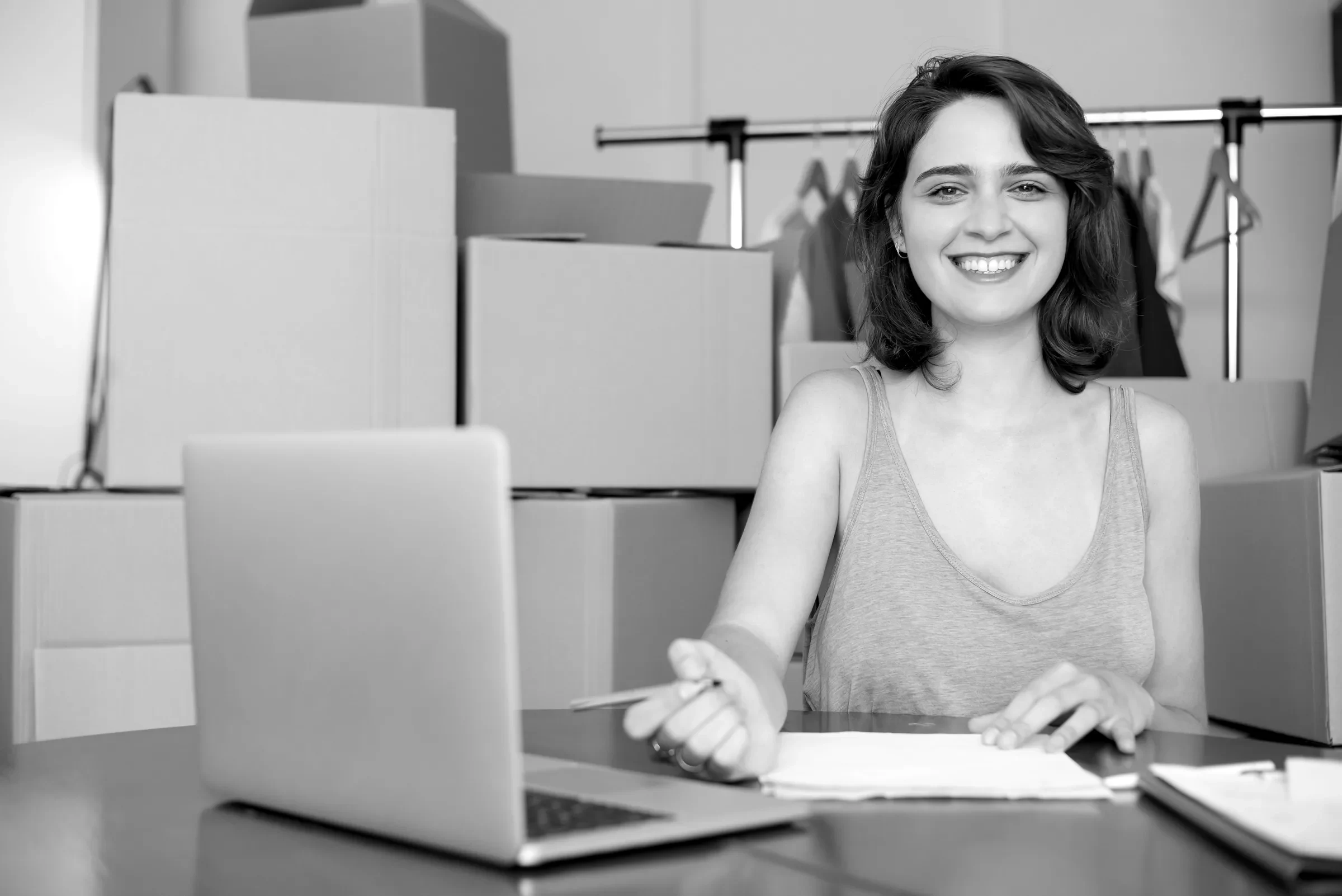 A seller at a laptop surrounded by stock boxes
