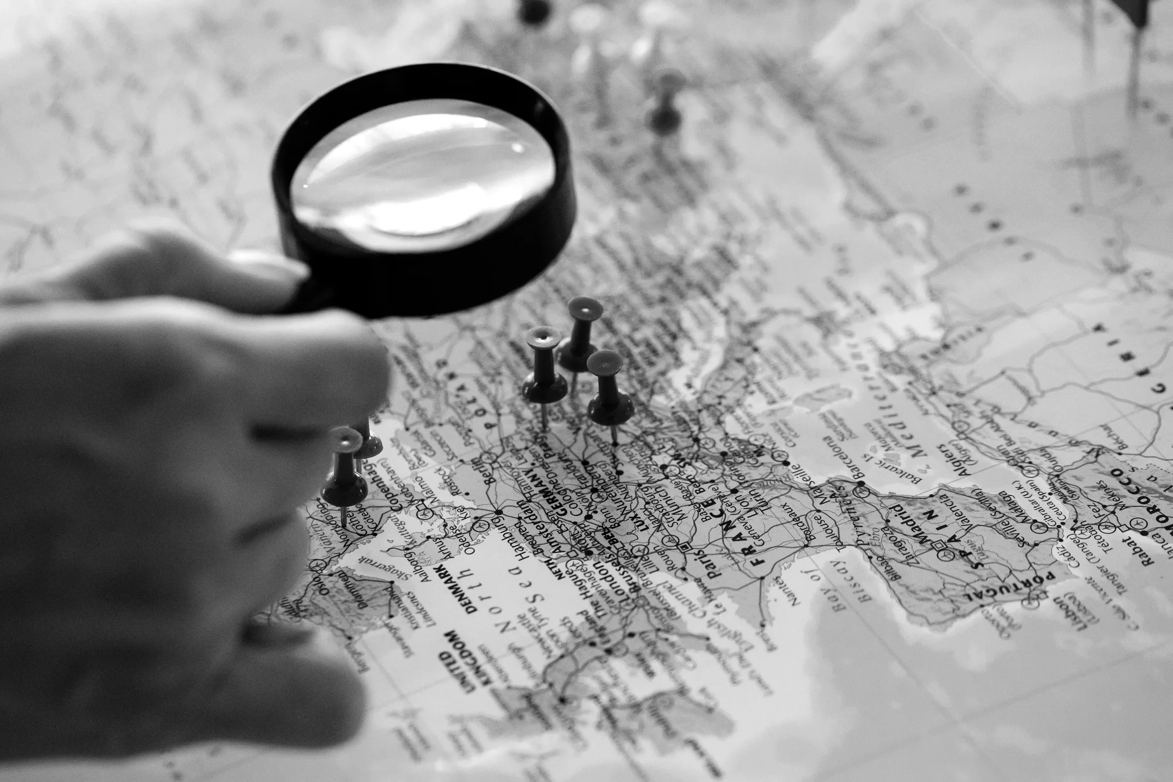 A magnifying glass over a world map with pins