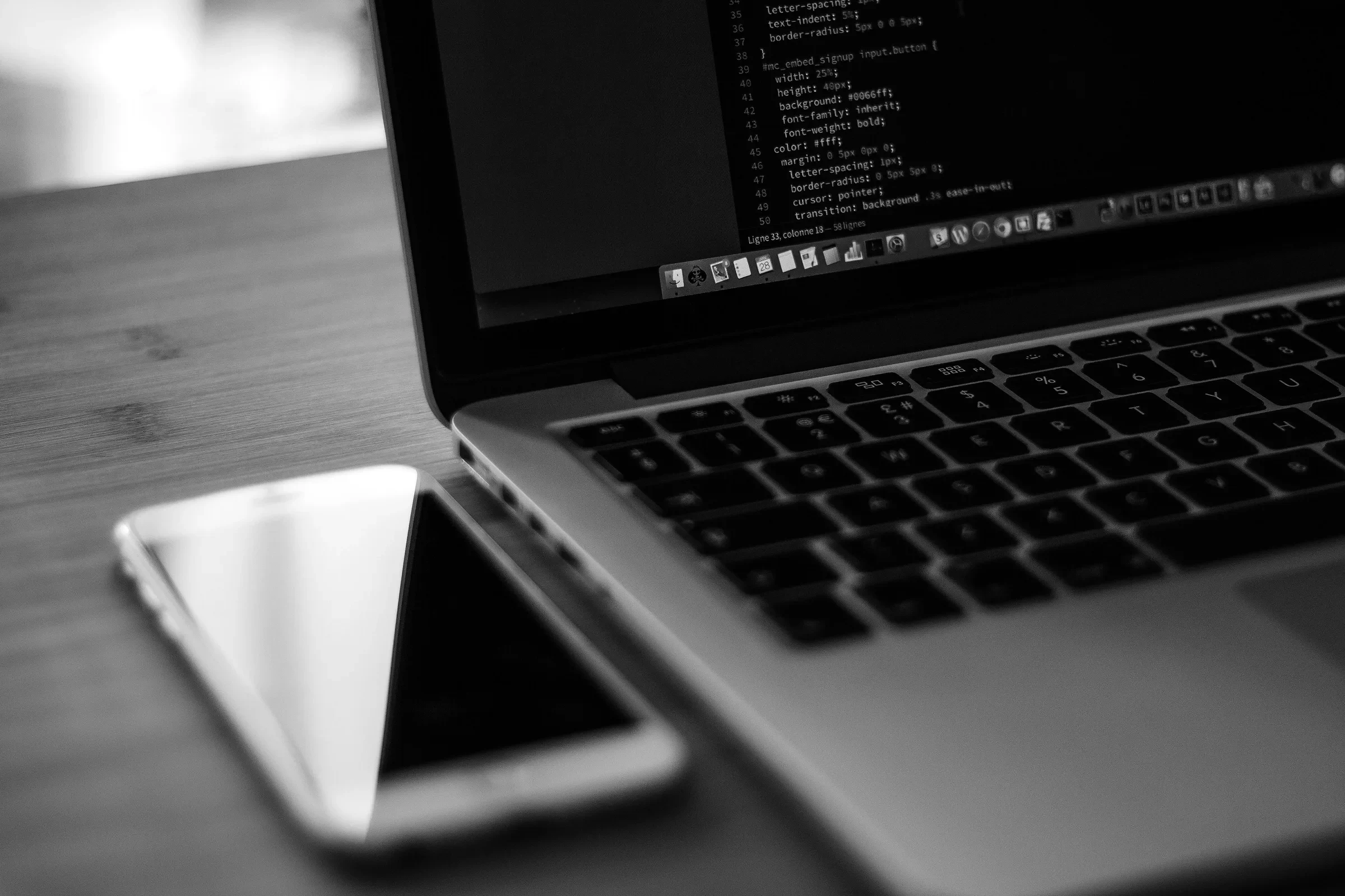 App code on a laptop beside a smartphone