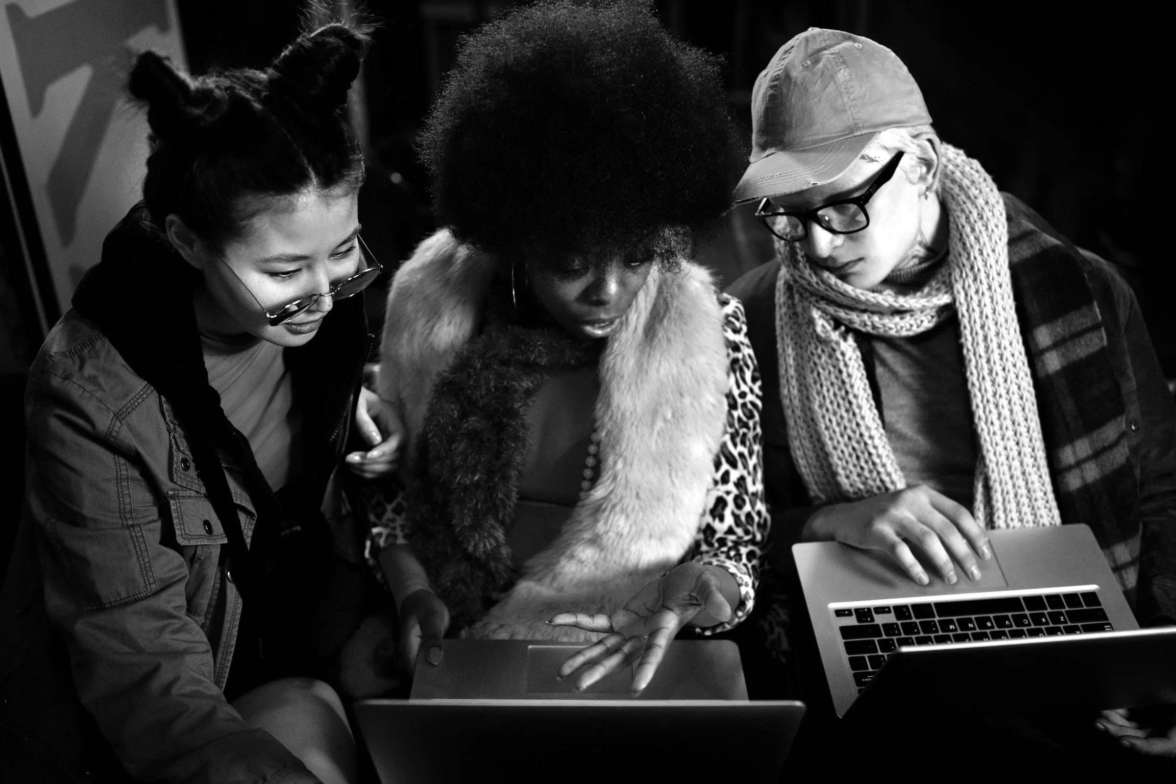 A group huddled around laptops in neon light