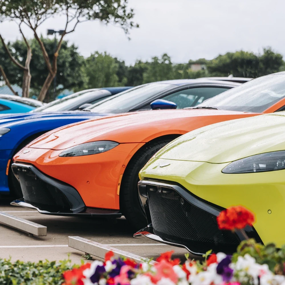 A row of sports cars in bright colours lined up on a dealership forecourt