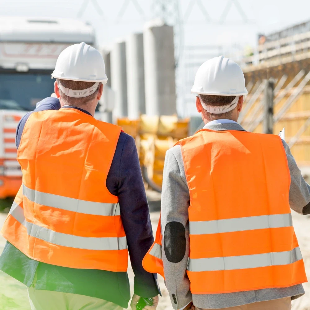 Two site supervisors in high-visibility vests walking through a construction site