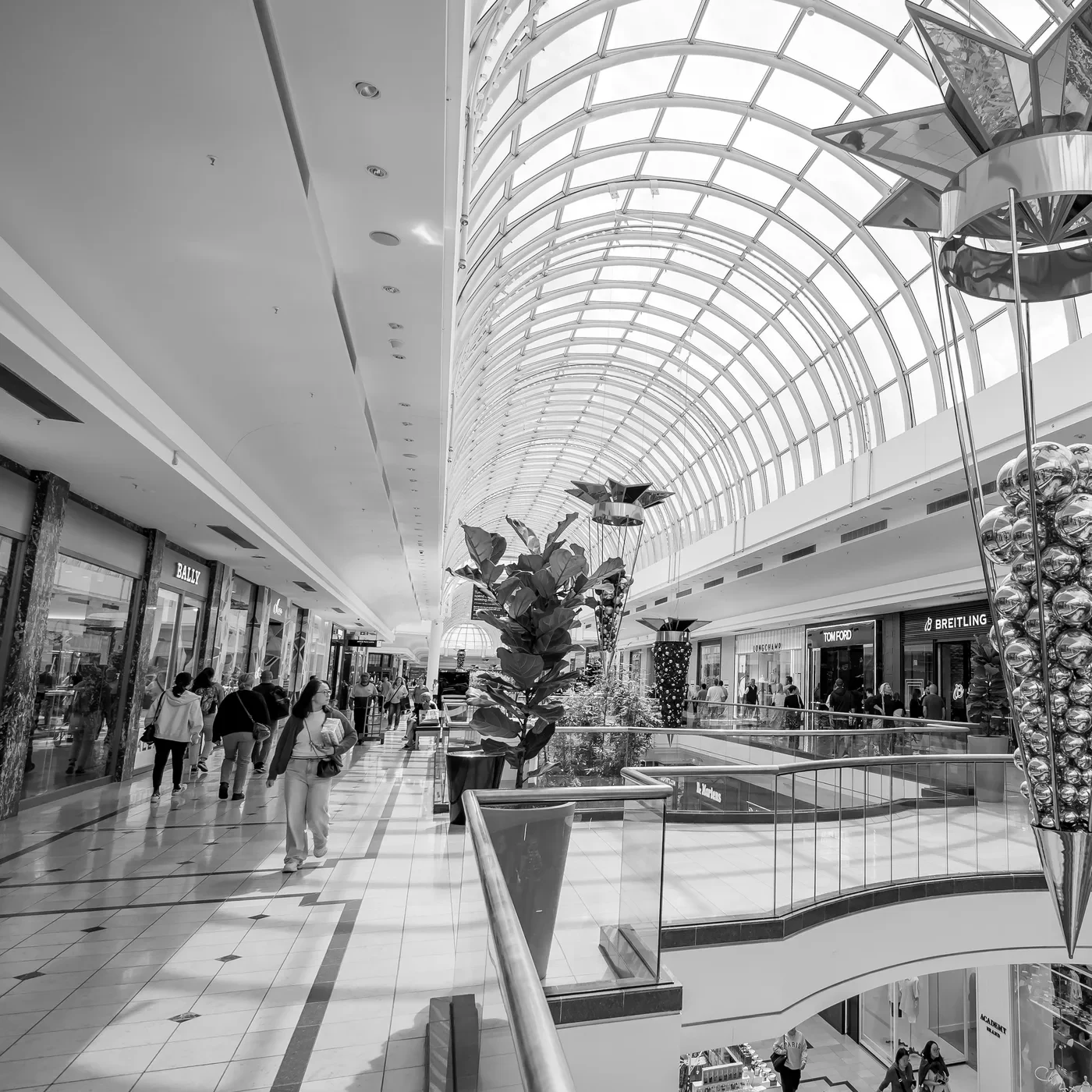 Shoppers passing storefronts inside a large shopping centre