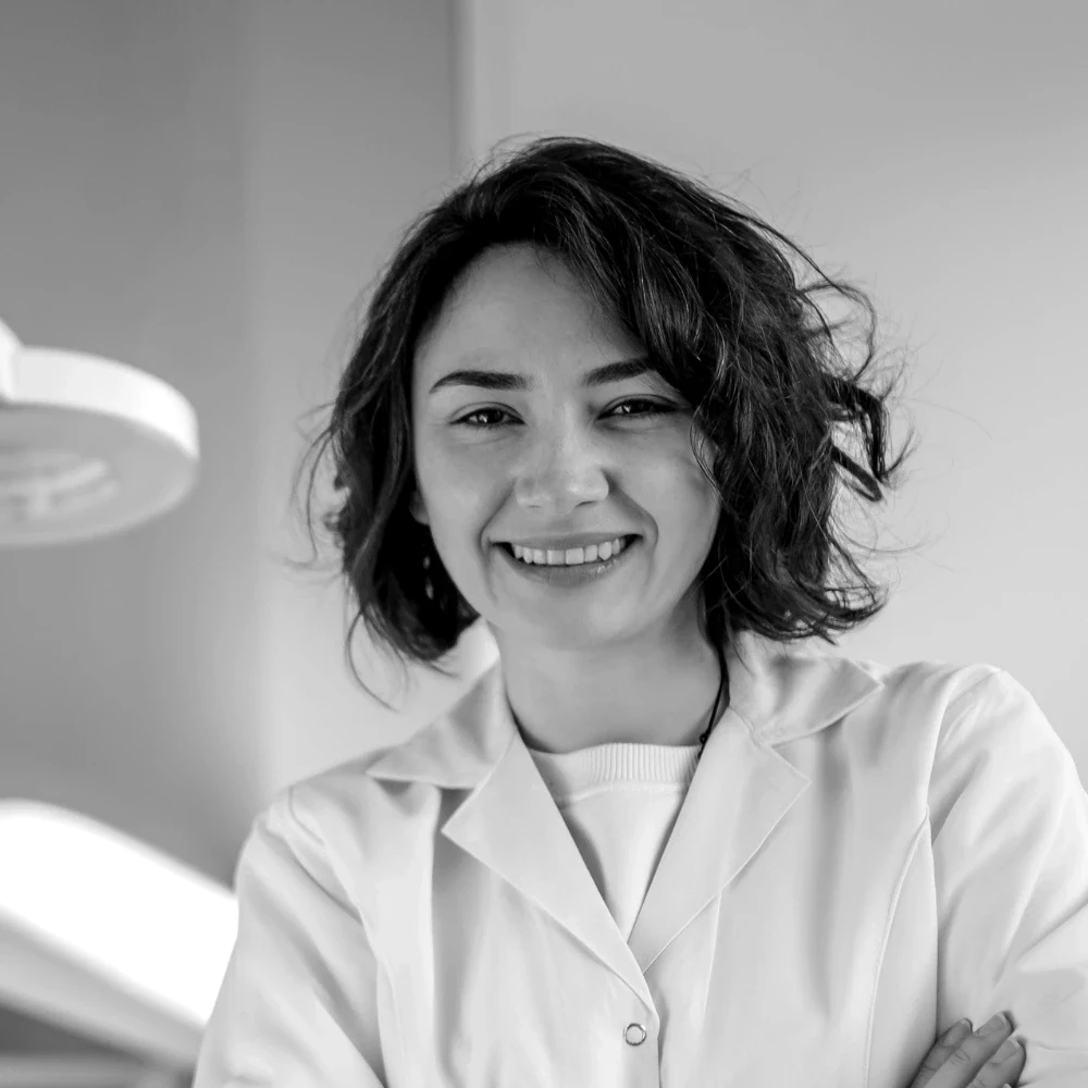 A smiling clinician in a white coat standing in a treatment room