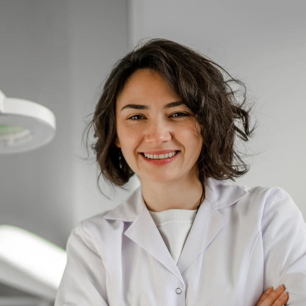 A smiling clinician in a white coat standing in a treatment room